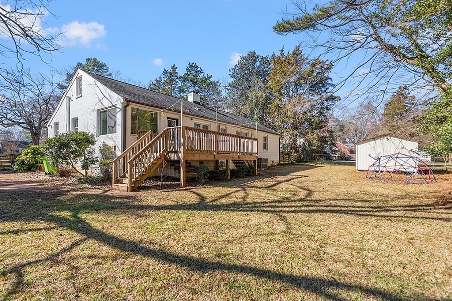 Back deck with wooded back yard behind house. Nice flat yard 