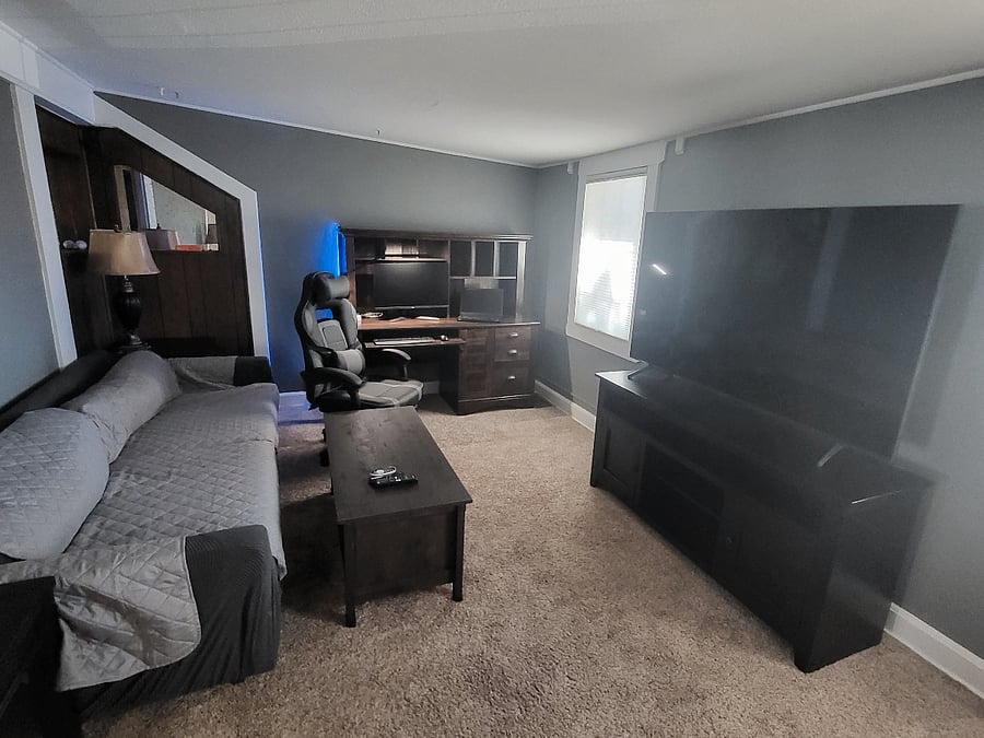 Living room with computer desk, chair, extra monitor, keyboard and mouse