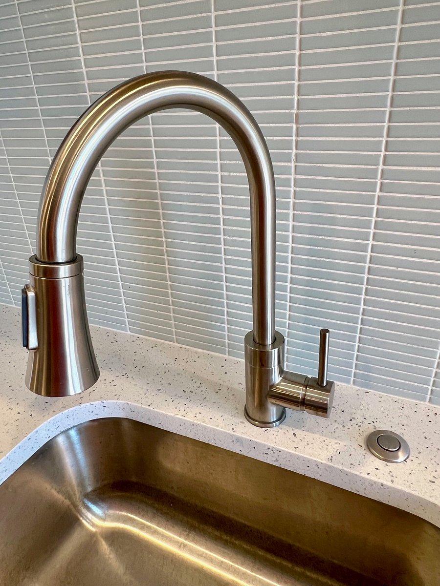 Gooseneck faucet with built-in sprayer. Garbage disposal in SS sink.