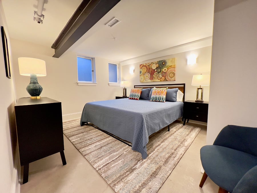 Spacious primary king bedroom with plenty of lighting and colorful artwork.
