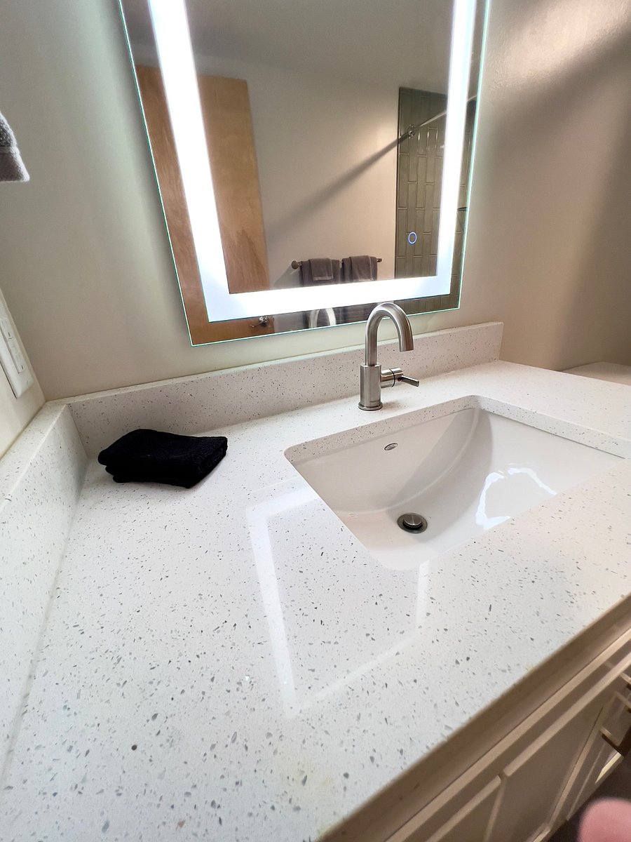 Quartz countertop, faucet, and mirror detail in primary bathroom.