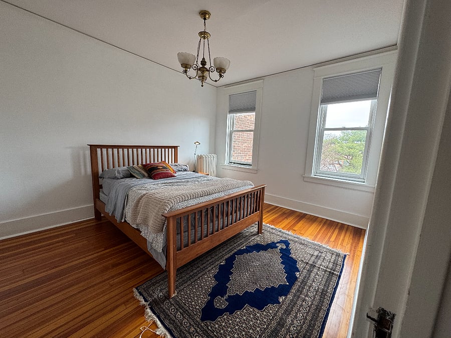 Third floor bedroom with a full sized bed, private bathroom and dresser.