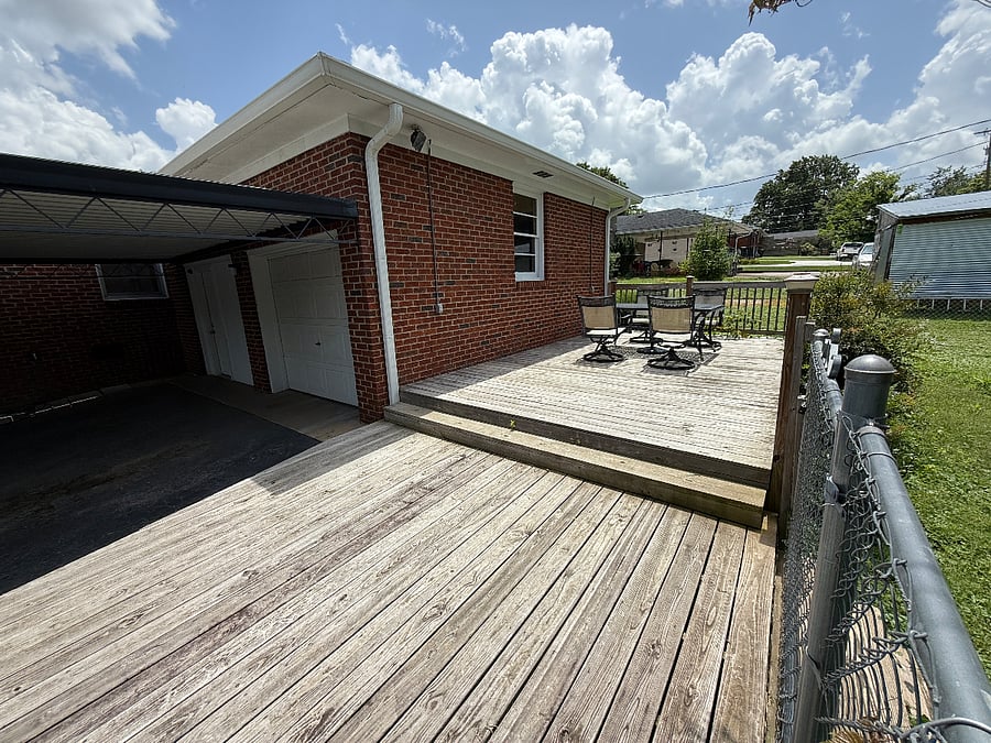 Patio and Dedicated parking: 2-tiered deck featuring a view of fenced-in yard, Shelby Park, 1-car garage door (other side is converted into a back entrance and houses the Washer & Dryer area), and a 2-car covered carport for ample dedicated parking options.