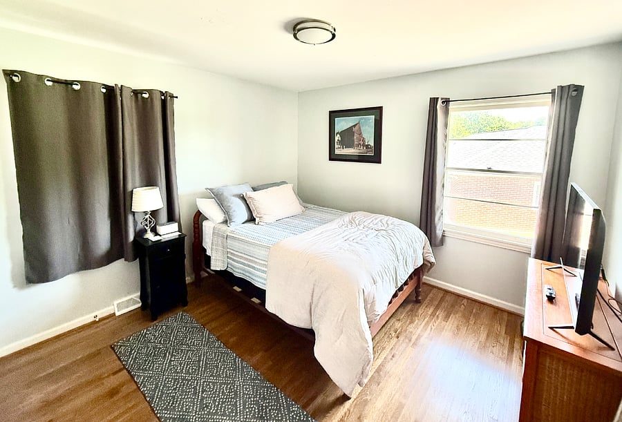 Bedroom 2: Charming full-size bedroom with cozy bedding, blackout curtains, 43" Smart TV, and a sound machine alarm clock