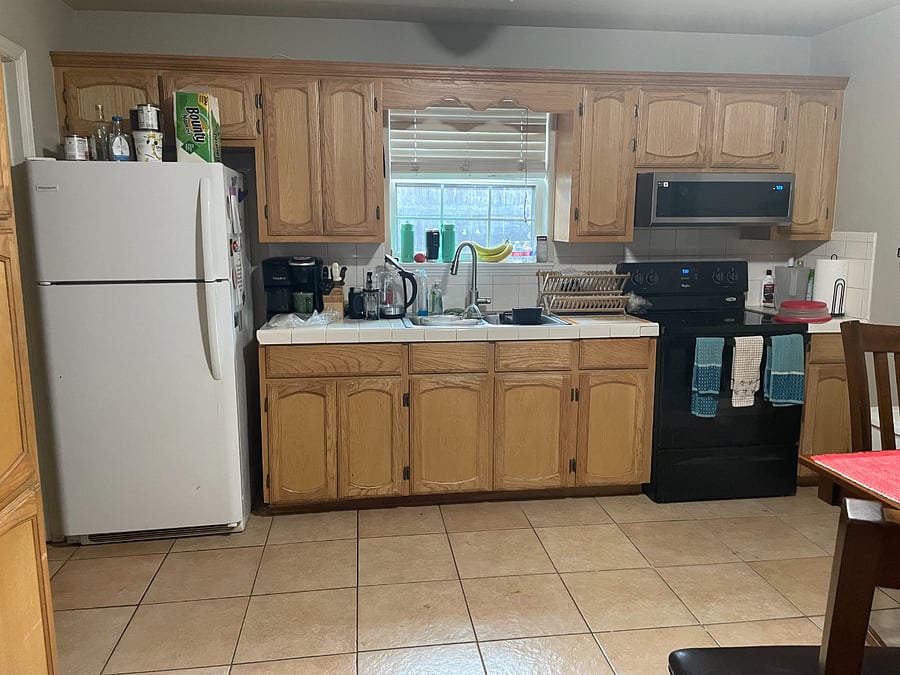 Kitchen with refrigerator that has ice cube storage bin and 4 ice cube trays. Keurig Duo Essentials coffee maker. Electric water heater and dish racks. Flat top stove and overhead microwave with fan. Kitchen fully outfitted with dishes, utensils, pots, etc.
