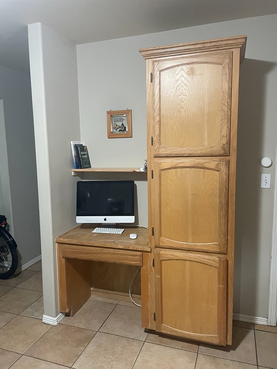 Kitchen pantry adjacent to kitchen workspace with small overhead shelf. Pantry has baking pans and additional space for food storage.