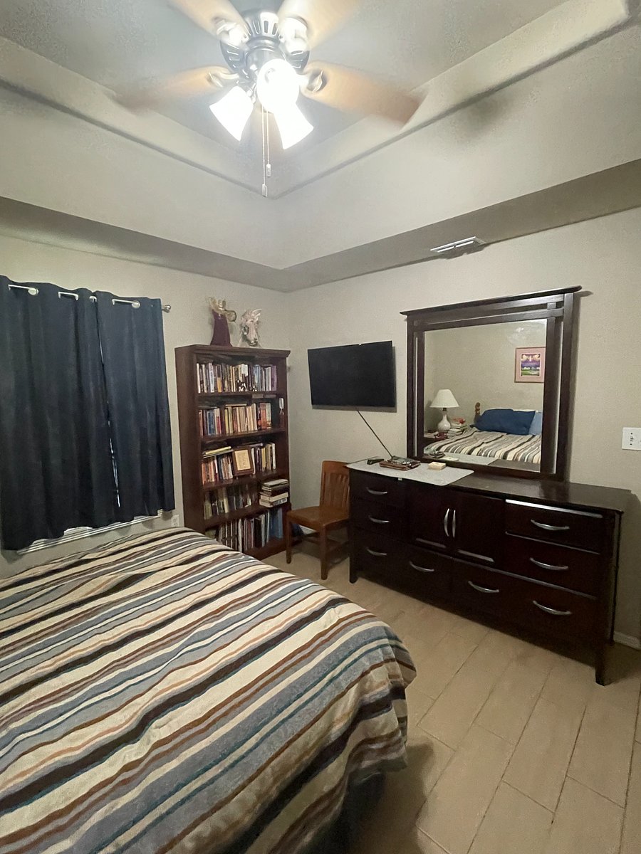 42" TV on wall opposite of queen bed. Large bureau with mirror and utility chair.