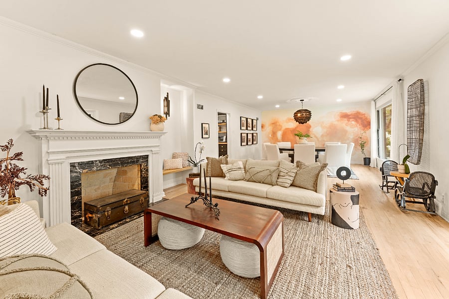 Living area with hardwood floors, marble fireplace surround and a light filled bay window.
