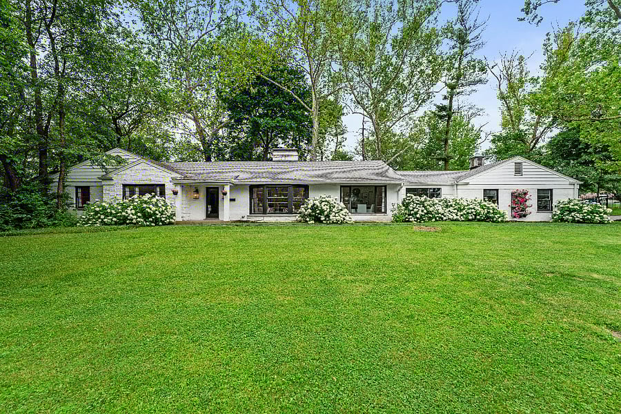 Single story home with a large front lawn and mature trees.