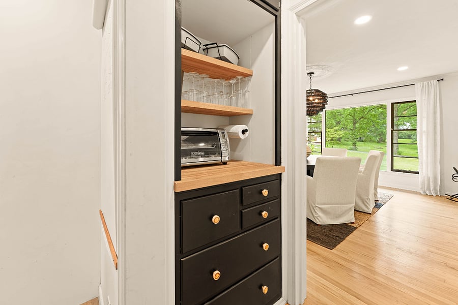 Butler's pantry stocked with serving dishes, barware, and a toaster oven.