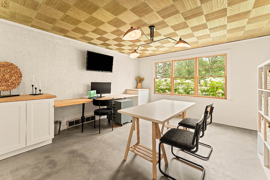 Home office with windows full of hydrangea blooms. A color printer capable of prints as large11x17 is in the cabinet to the left. The cabinet to the right is open for storage as well as the 2 storage cube cabinets on the rear wall. A table for additional workspace is behind the workstation and a wall mounted T.V. is available as well.