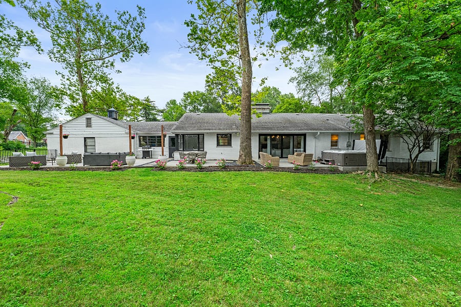 Back of house with a hot tub, outdoor lounge area, a patio area, and a yard