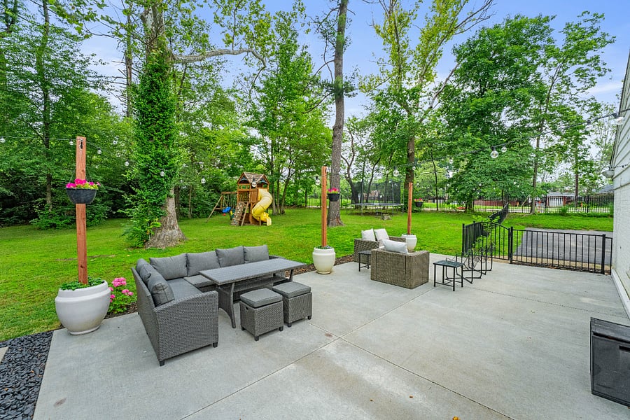 View of patio with the playground, trampoline, and zip line beyond