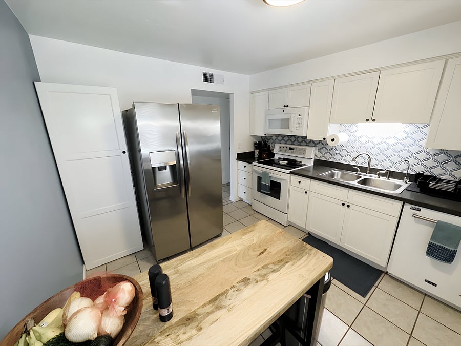 The kitchen featuring a dishwasher, full size fridge/freezer, oven, stove top, and all utensils to cook delicious meals