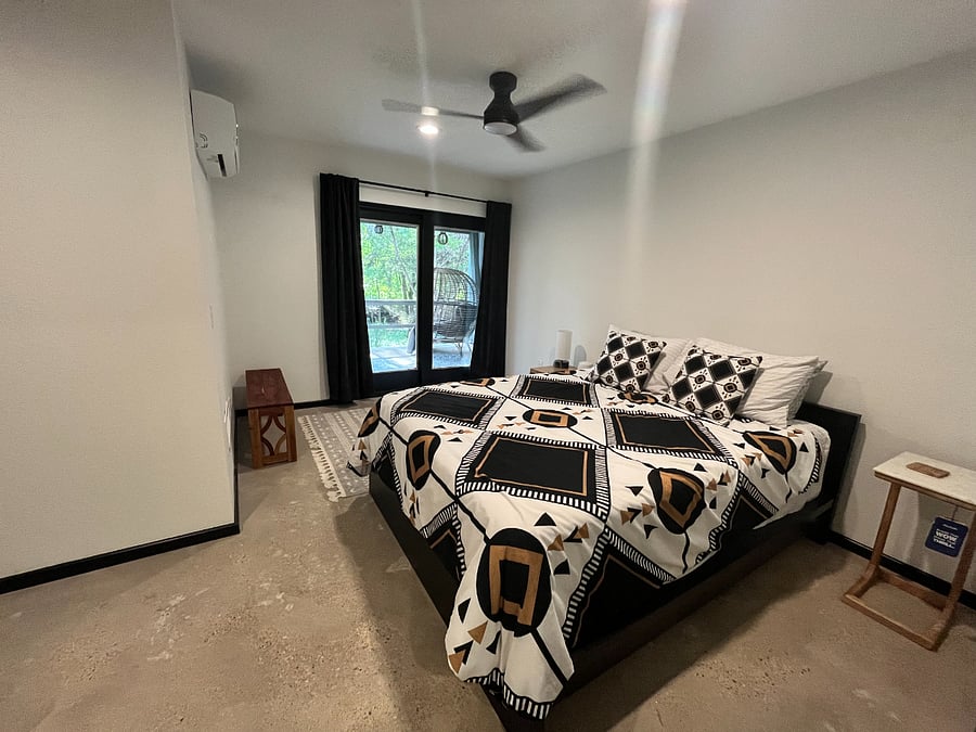 Bedroom with queen bed and sliding doors leading to back patio and laundry closet.
