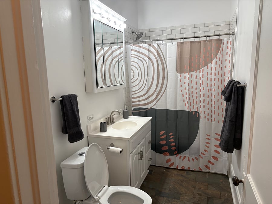 Bathroom with white subway tile and mirrored cabinet.