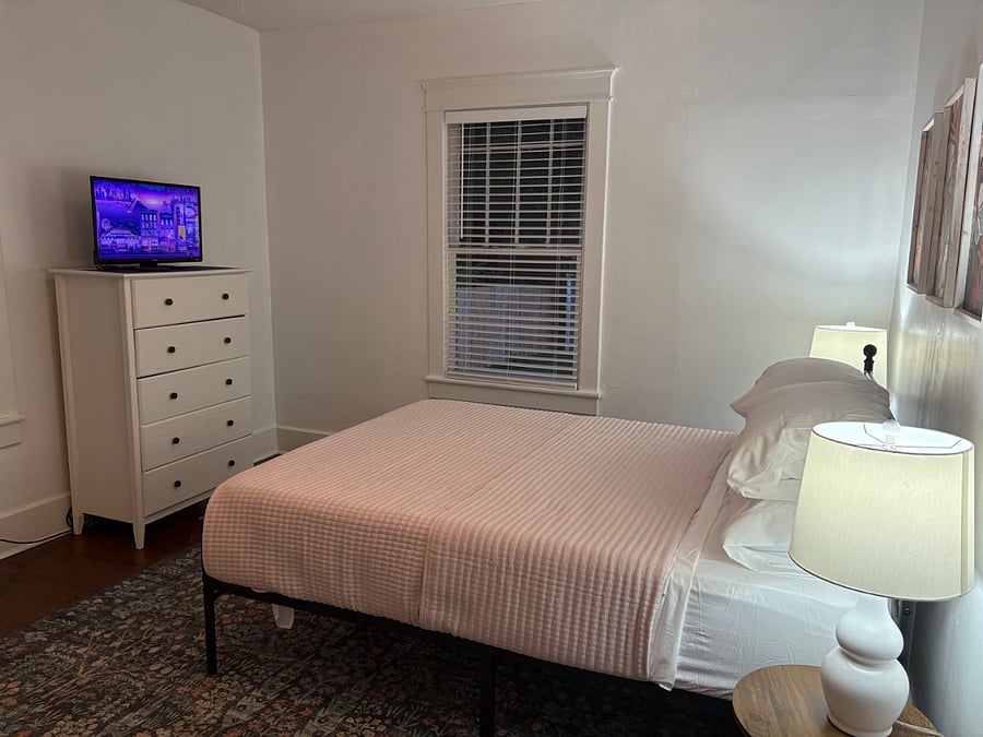 2nd bedroom with smart tv and dresser. Phone charger by side of bed.