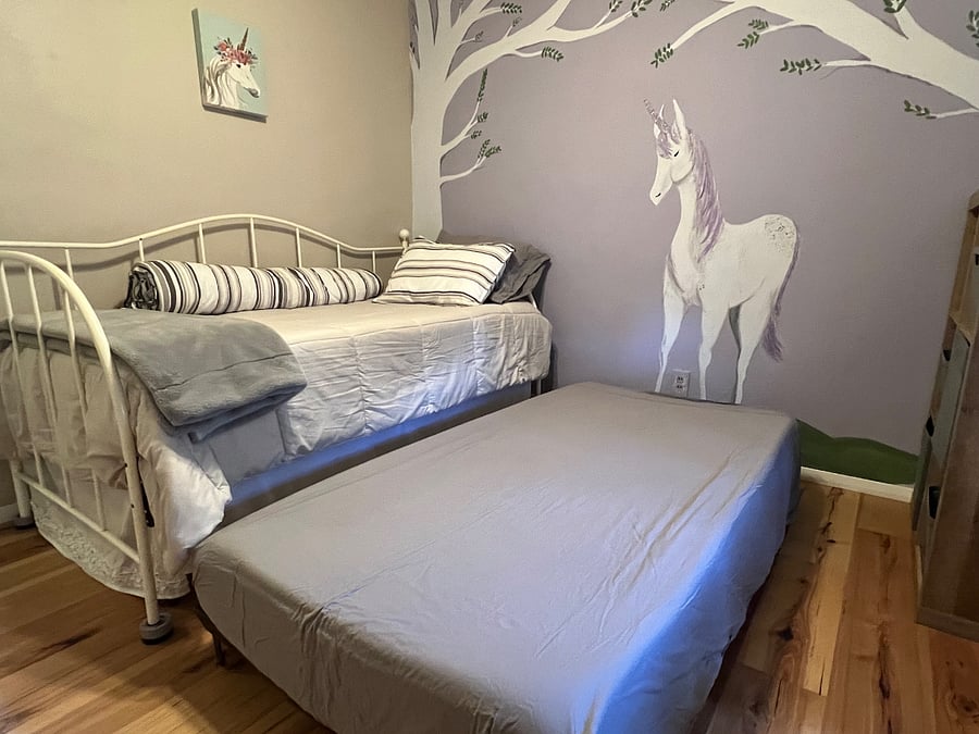 The twin bedroom has a day bed with a trundle bed rolled underneath. The window has a blackout rollershade. This was my granddaughter's room and we painted the mural. We haven't had the heart to paint over it...