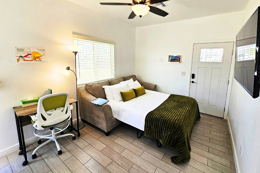 Queen size sofa bed with linens and pillows stored in dining bench.