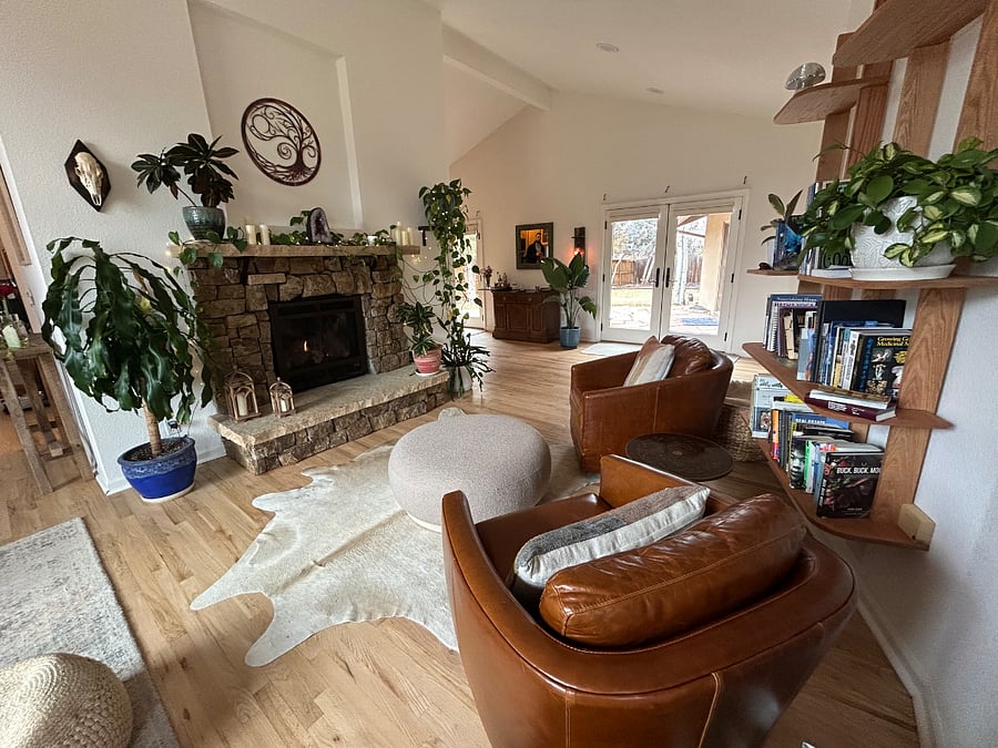 Light filled living room with gas fireplace, huge green velvet couch, and two sets of french doors leading to backyard