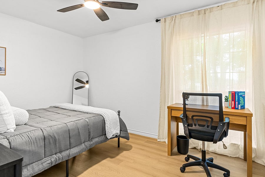 Large room with workspace, closet and nightstand.
