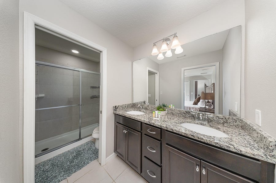 Beautifully designed bathroom with a spacious walk-in shower, granite countertops, and contemporary lighting.