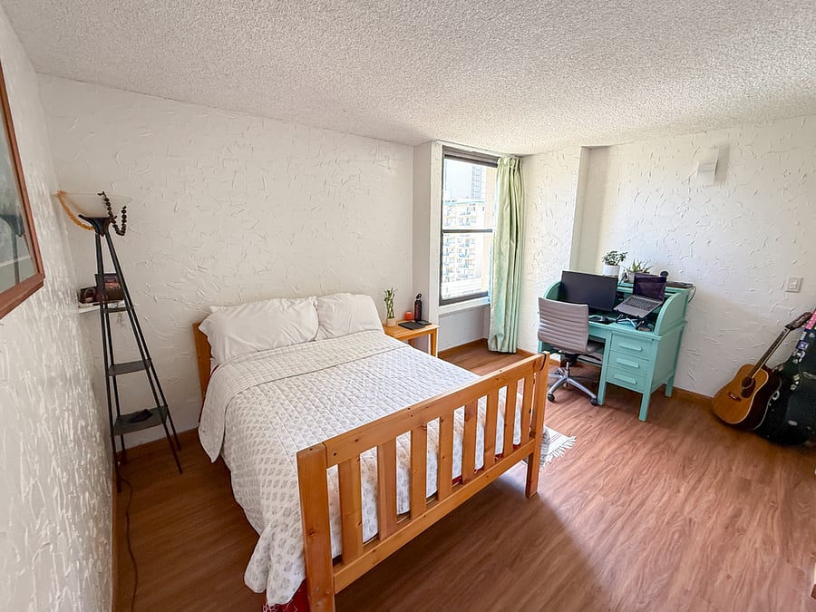 The bedroom for rent comes with a full size bed, linens, pillows, desk / chair, lamp, and a bedside table, and has a similar view as the view from the living room.