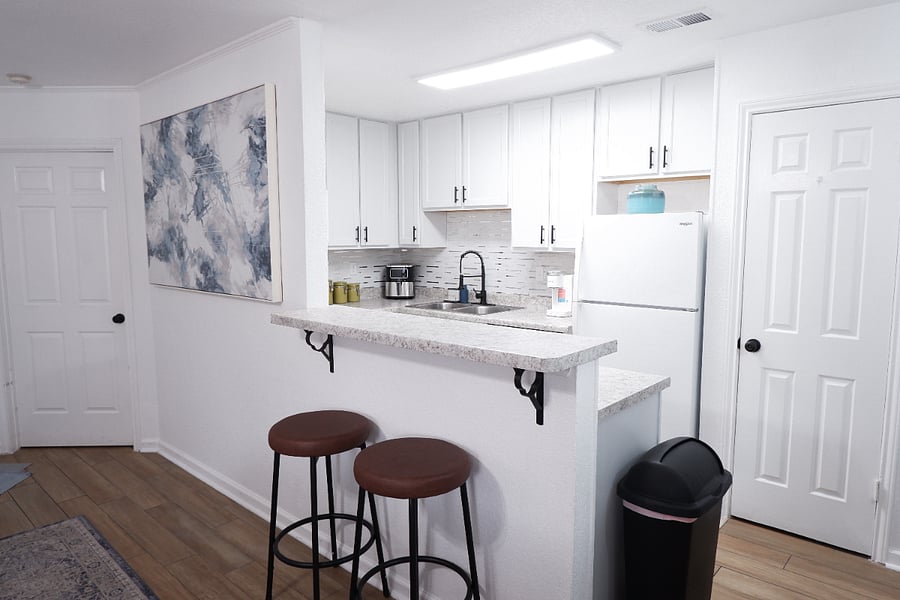 Bright open dining area with a renovated kitchen featuring essential cookware and appliances perfect for everyday meals.