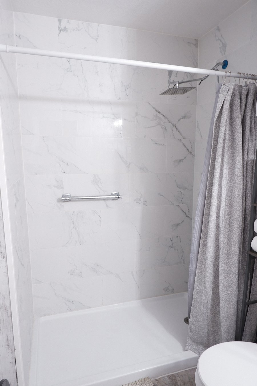 Renovated walk-in shower with modern tile and relaxing rainfall shower head designed for comfort and style.
