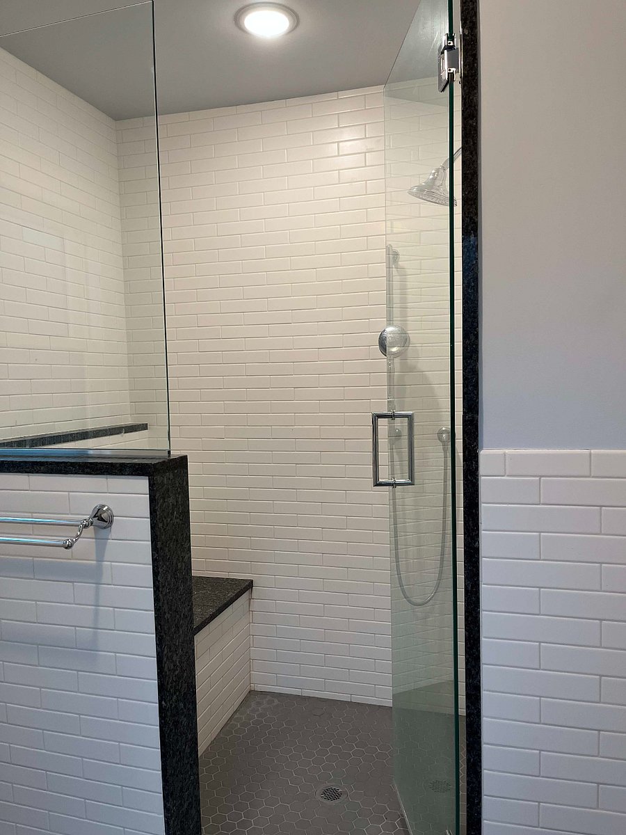 Second floor bathroom walk-in shower (another view). There is a bench, tall shower head, and handheld shower.