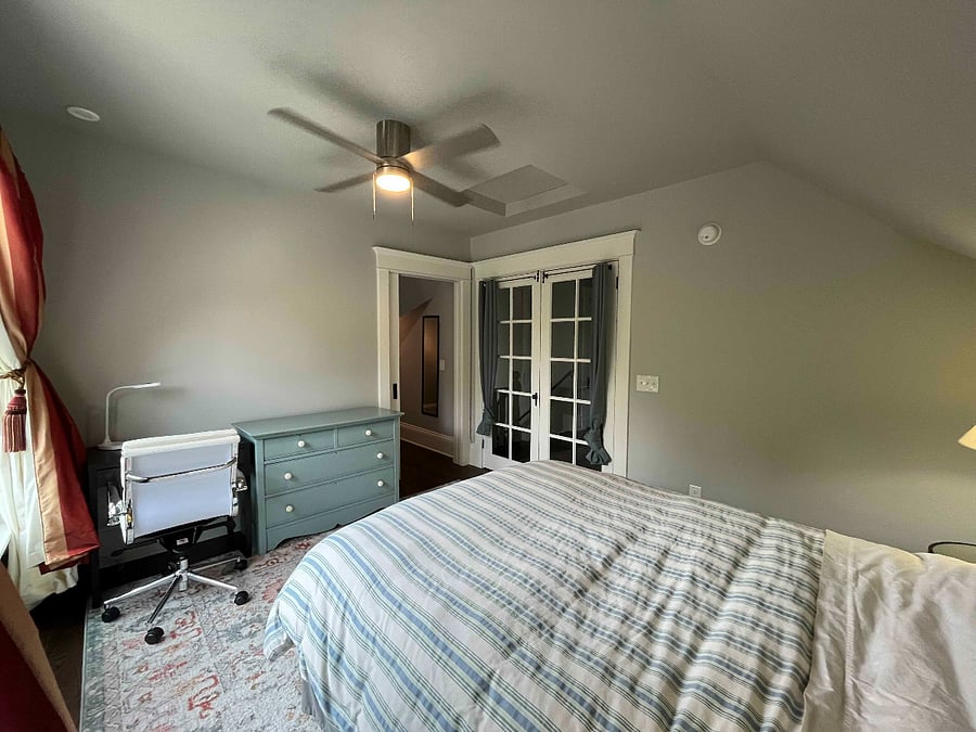 Attic bedroom (queen bed) with view of walk-in closet door. The closet has a pocket door.
