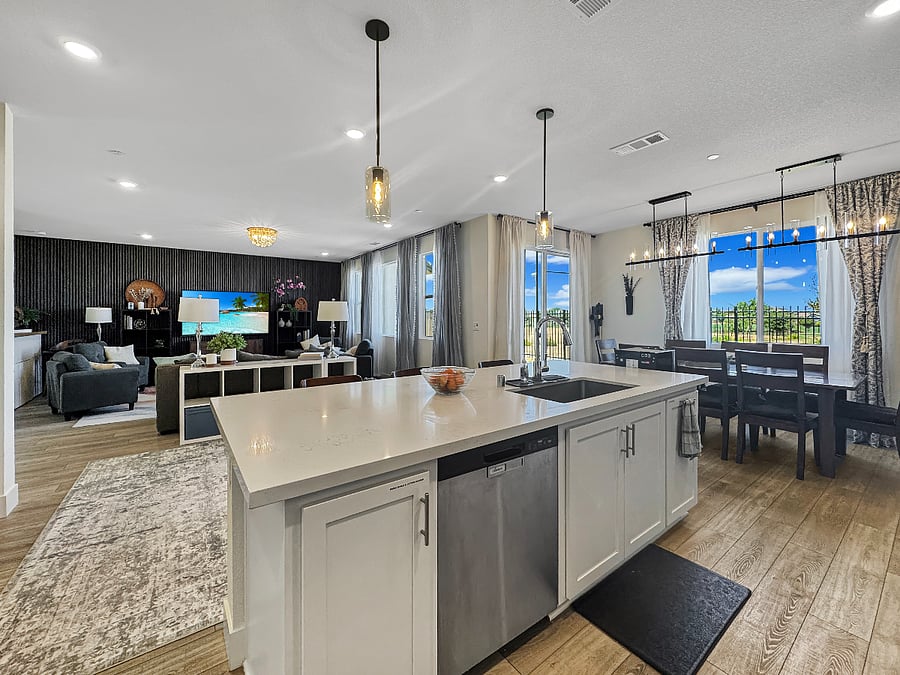 Huge kitchen island with three modern decorative chairs and gorgeous lighting.