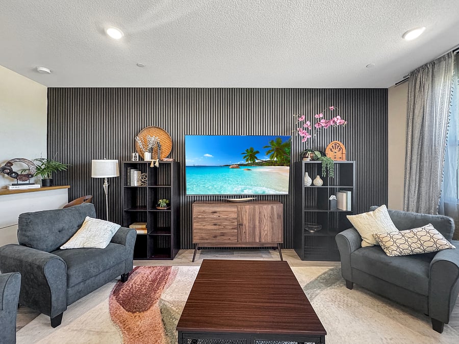 Living room featuring a grand view of the park. Furnished with extra deep couch, four comfortable sofa chairs, extra large 75" tv and tall task chair at a beautiful wood table top task area above Ikea cabinets.