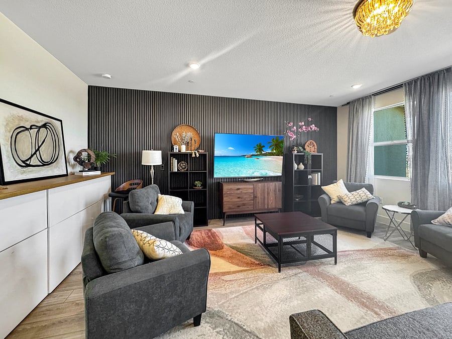 Living room featuring a grand view of the park. Furnished with extra deep couch, four comfortable sofa chairs, extra large 75" tv and tall task chair at a beautiful wood table top task area above Ikea cabinets.