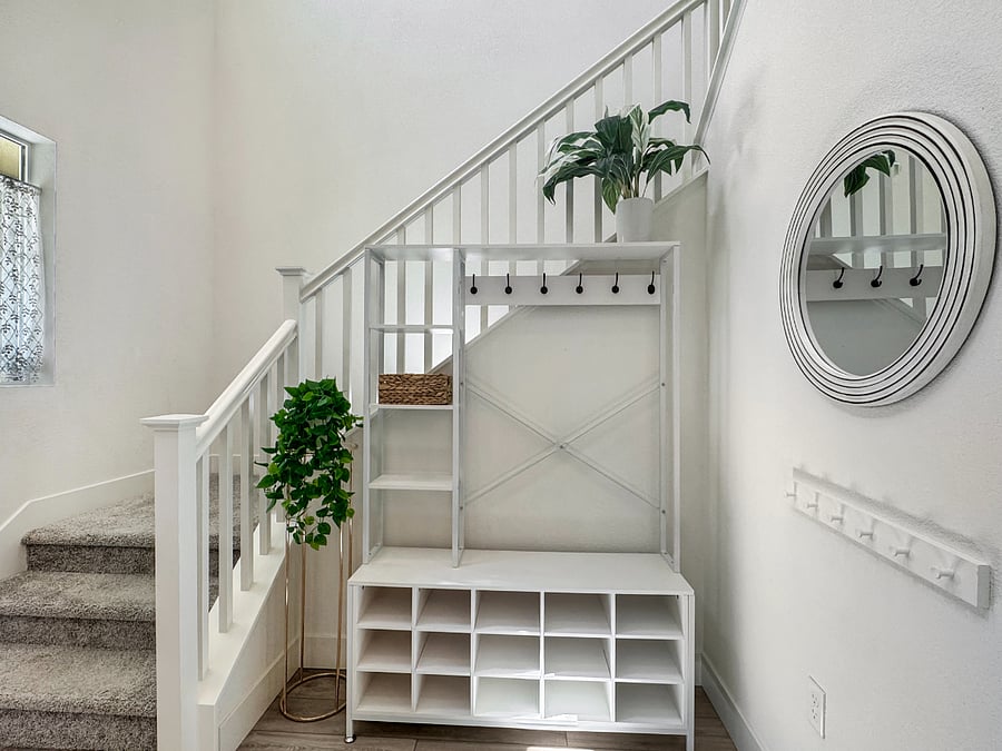 Grand entrance equipped with coat hangers for adults and children, shoe cubbies, and mirror.