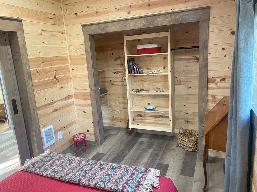 The bedroom offers generous closet space, including built-in shelving at each end for easy storage and organization.