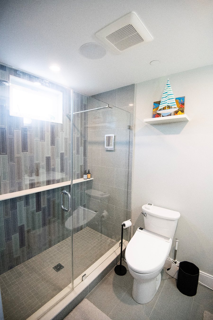 The on-suite bathroom has a large glass enclosed shower with rain head and handheld sprayer - the convenient shelf holds a plethora of personal care items.
