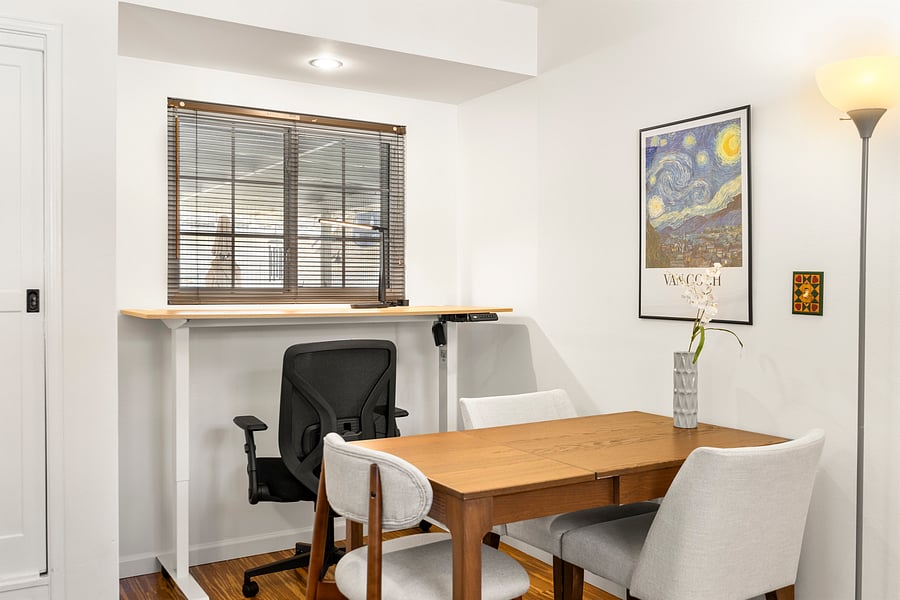 The space includes an adjustable standing desk and an extendable dining table.