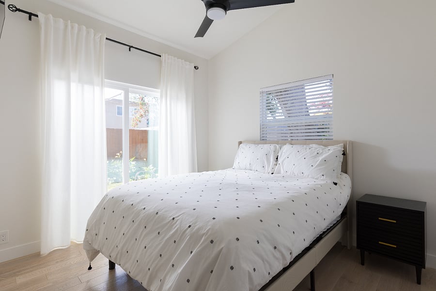 Bedroom with queen sized bed and sliding glass doors looking into the backyard.