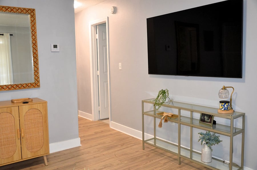 Unwind in the living space with a mounted smart TV and chic touches for a cozy, curated vibe.