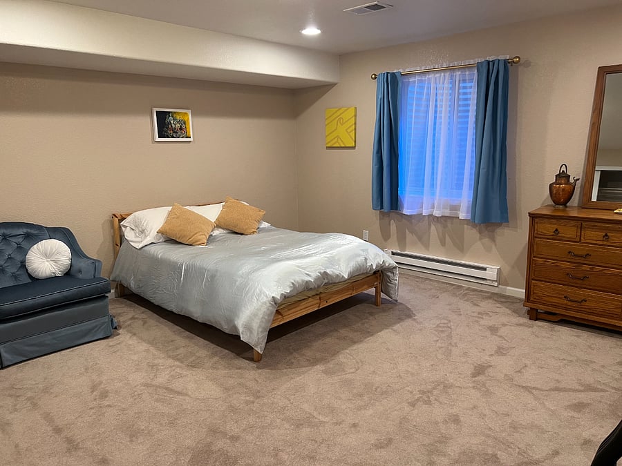 Large basement bedroom suite with a full-size bed and blackout curtains.
