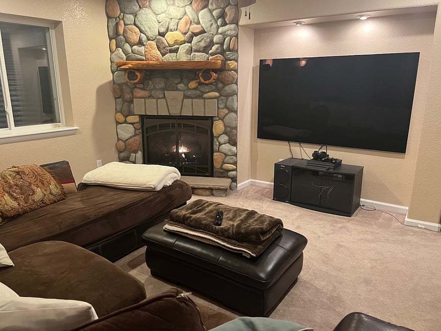 Comfy basement entertainment area with large screen TV, gas fireplace, and oversized comfy couch.