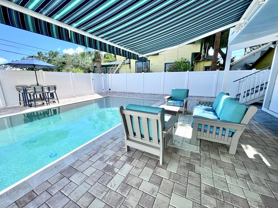 Patio table with umbrella, couch and chairs for dining outside or entertaining.
