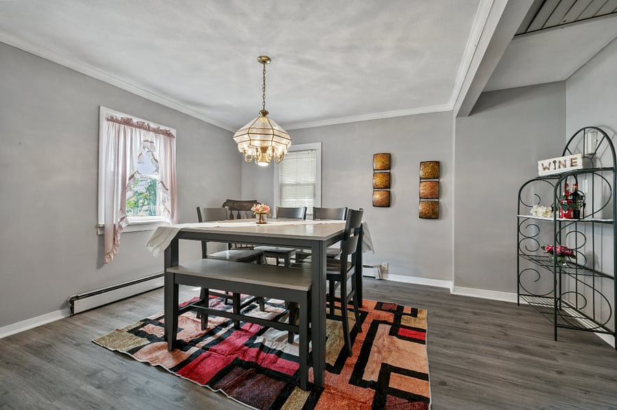 Dining room able to seat 8 people with 4 chairs and a bench and wine rack
