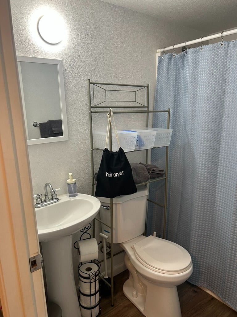 Bathroom with storage, hairdryer, first aid kit, and tub/shower combo.