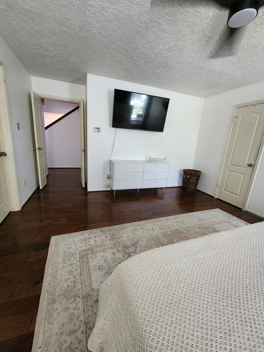 Master bedroom downstairs with TV, dresser and wicker laundry hamper