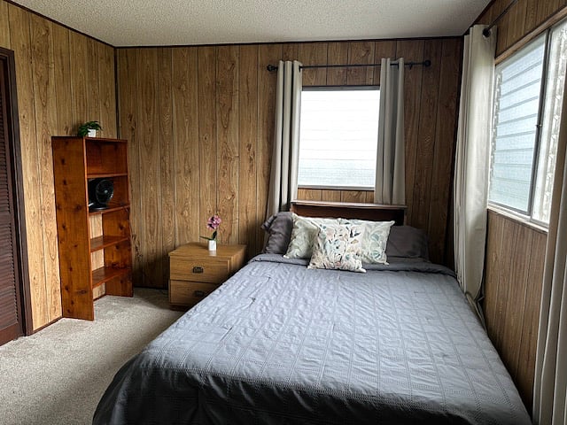 Second bedroom with queen bed, built-in shelving, and blackout shades for restful sleep.
