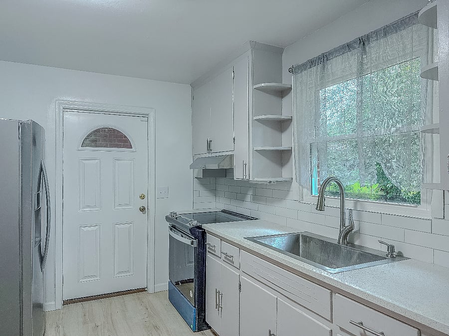 Full kitchen, with full stove, refrigerator, microwave, dishes, and cookware. The kitchen door leads to the laundry room with a washer/dryer stackable and some storage.