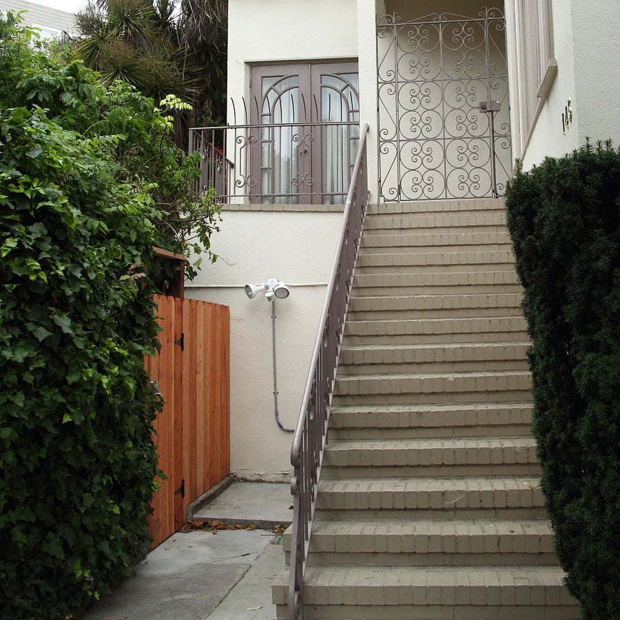 Apartment entrance through gate to left of house stairs