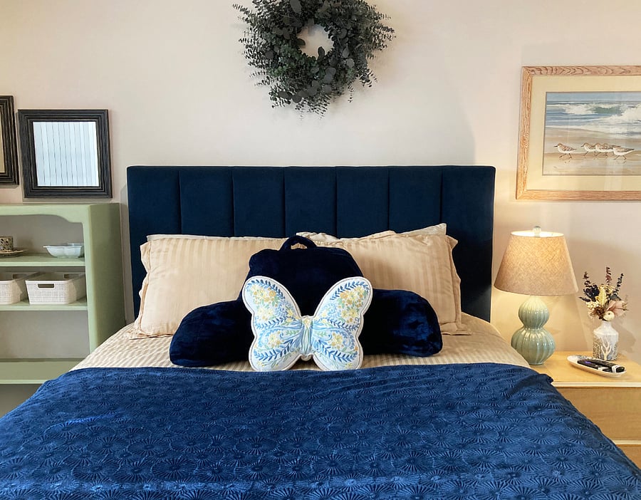 Queen bed with pillows incl. TV situp pillow, bookcase, nightstand, wall wreath, beach art